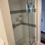 Tile and stone shower with glass door and silver head and hardware