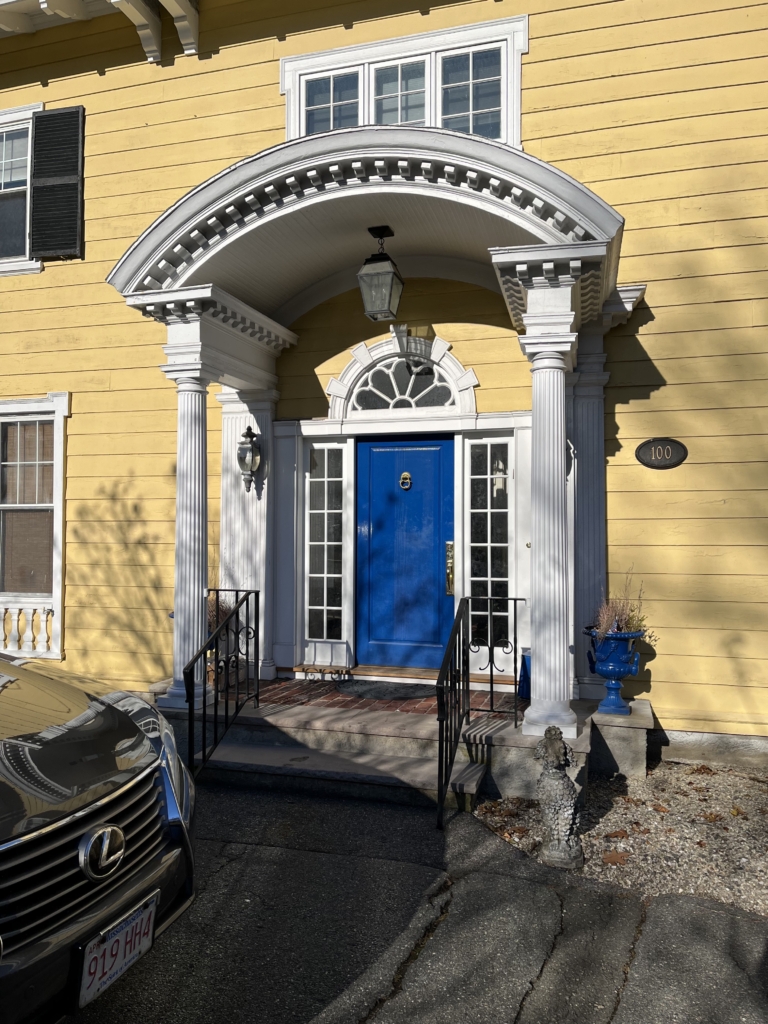 blue door brand new installation on exterior of yellow home with white awning and windows around the frame with a brick walk up steps for home accessibility and aesthetic