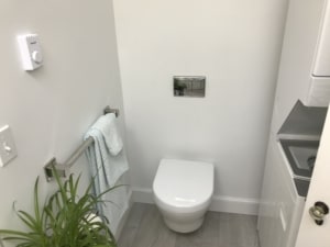 tankless toilet installed during a bathroom remodel against the wall with a switch attached for easy flushing